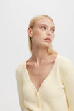 Woman wearing a light yellow cardigan against a white background