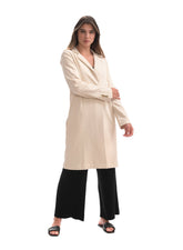 Woman wearing a beige long coat and black pants on a white background