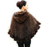 Woman wearing a brown knitted poncho with fur trim on a white background
