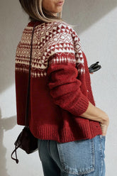 Woman in red and cream Fair Isle cardigan with blue jeans and black shoulder bag, side-back view.