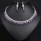 Necklace and earrings set with purple and clear gemstones on a black background