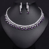 Necklace and earrings set with purple and clear gemstones on a black background