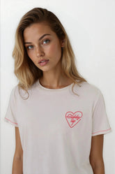 Woman wearing a white t-shirt with a red heart design on a plain background