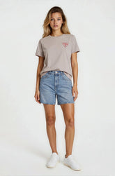Woman wearing a gray t-shirt with a logo and denim shorts on a white background