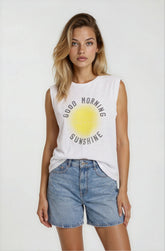 Woman wearing a white sleeveless shirt with 'Good Morning Sunshine' print and denim shorts on a white background