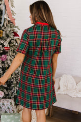 Back view of green and red plaid short sleeve shift dress by a Christmas tree