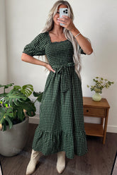 Woman wearing a green plaid smocked square neck maxi dress with tie waist and boots