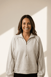 Woman wearing a beige pullover with a neutral background