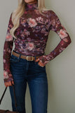 Person wearing a floral long-sleeve top and blue jeans against a plain background