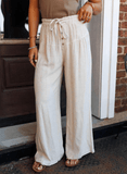 Person wearing beige wide-leg pants with a brown top and sandals, standing on a step.