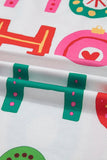 Close-up of white fabric with colorful holly leaves, ornaments, and red accents.