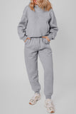 Model in light gray heathered sweatshirt and joggers with beige sneakers.