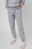 Person wearing a gray tracksuit with white sneakers on a light gray background
