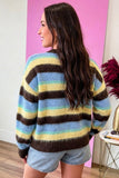Back view of woman in fuzzy striped knit sweater with brown, yellow, blue, and mint green bands