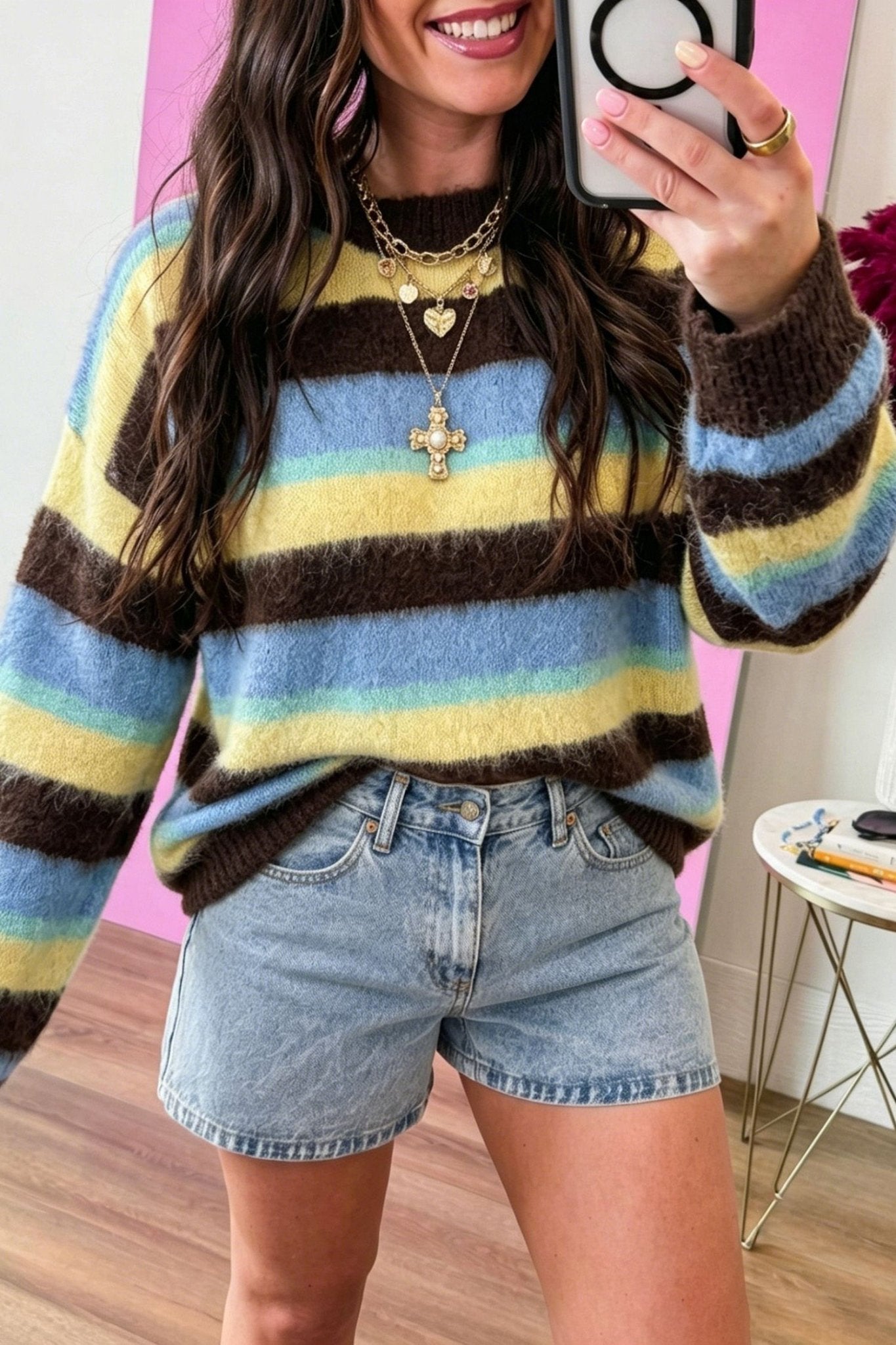 Woman in mirror selfie wearing fuzzy long-sleeve striped sweater in brown, yellow, blue, and mint green