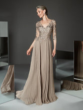 Woman wearing a long, elegant dress with floral embellishments in a minimalistic setting.
