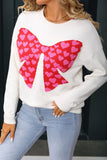 White sweater with a red heart bow design worn by a person.