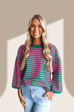 Woman wearing a striped shirt and jeans against a beige wall