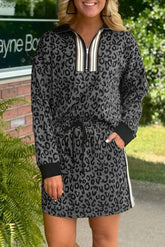 Woman wearing a leopard print dress with a zipper in front, standing outdoors.