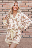 Woman in cream animal-print lounge set with button-front top and tie-waist shorts.