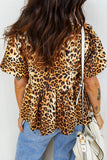 Person wearing a leopard print top and blue jeans, holding a white handbag.