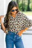 Woman wearing a leopard print blouse and blue jeans outdoors.