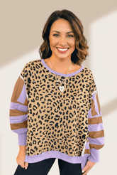 Woman wearing a leopard print top with purple and brown sleeves against a neutral background