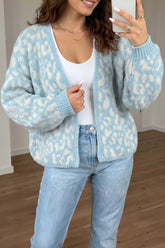 Woman in light blue-white patterned cardigan, white tank top, and light blue jeans taking a mirror selfie.