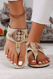 Gold embellished sandals worn with white pants on a blurred background