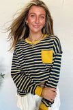 Woman wearing a navy and yellow striped long-sleeve top with a yellow pocket against a light background