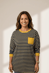 Woman wearing a striped shirt with a yellow pocket on a plain background