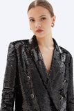 Woman wearing a black sequin blazer on a white background