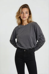 Woman wearing a gray long-sleeve top with star designs on a white background