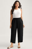 Woman wearing a white sleeveless top and black wide-leg pants on a plain background