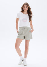 Woman wearing a white t-shirt and light gray shorts on a white background