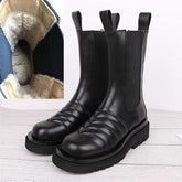 Black leather boots with a close-up of the interior lining on a light wooden floor.