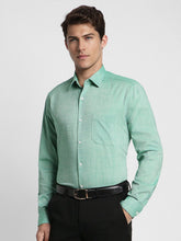 Man wearing a light green checkered shirt with black pants on a white background