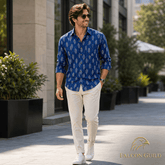 Man walking outdoors wearing a blue patterned shirt and white pants, with 'Falcon Guild' logo.