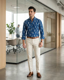 Man in a blue patterned shirt and beige pants standing in an office setting