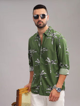 Man wearing a green shirt with palm tree pattern against a gray background