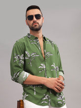 Man wearing a green patterned shirt and sunglasses on a gray background