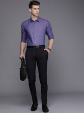 Man wearing a purple dress shirt and black pants against a gray background