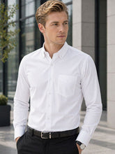 Man wearing a white dress shirt and black pants standing outdoors.
