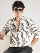 Man wearing a patterned shirt and sunglasses against a plain background