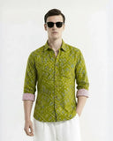 Man wearing a green patterned shirt and sunglasses on a white background