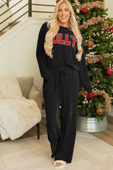 Woman wearing a black outfit with 'Bolly' text in a festive indoor setting with a Christmas tree.