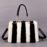 Black and white striped handbag with fur trim on a gray background