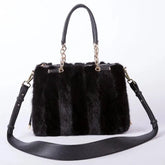 Black fur handbag with gold accents on a white background