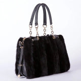 Black fur handbag with gold accents on a white background