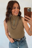 Woman taking a mirror selfie wearing a brown sleeveless top and blue jeans, with layered necklaces and bracelets.